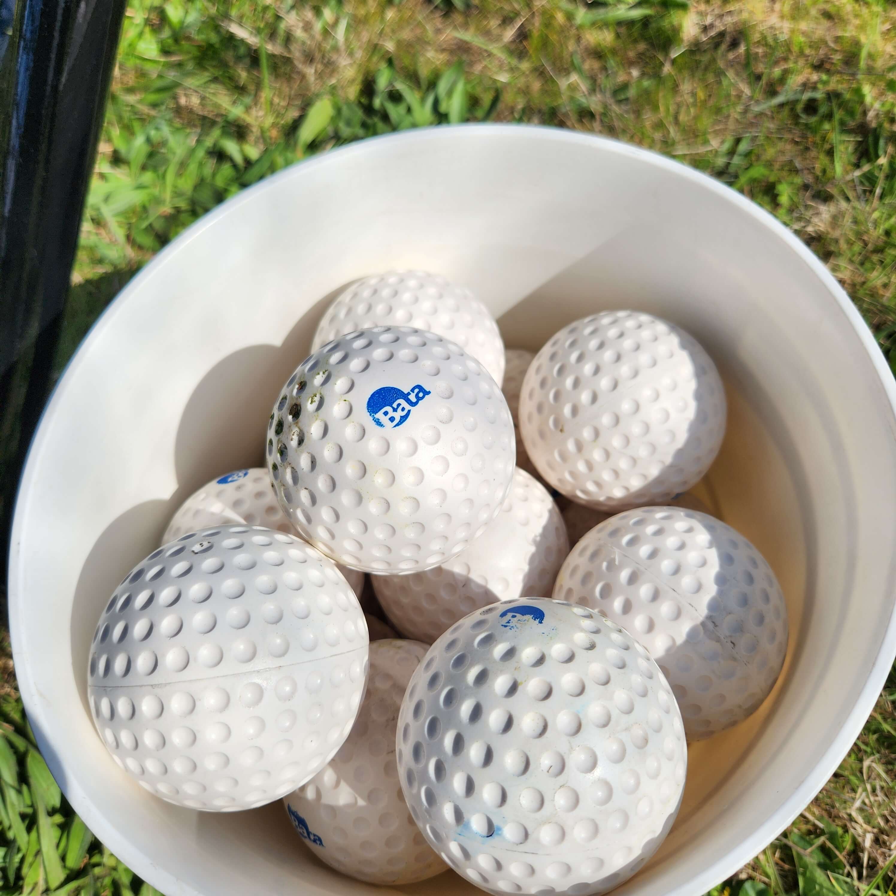 Lightweight bata dimpled baseballs in a bucket on grass