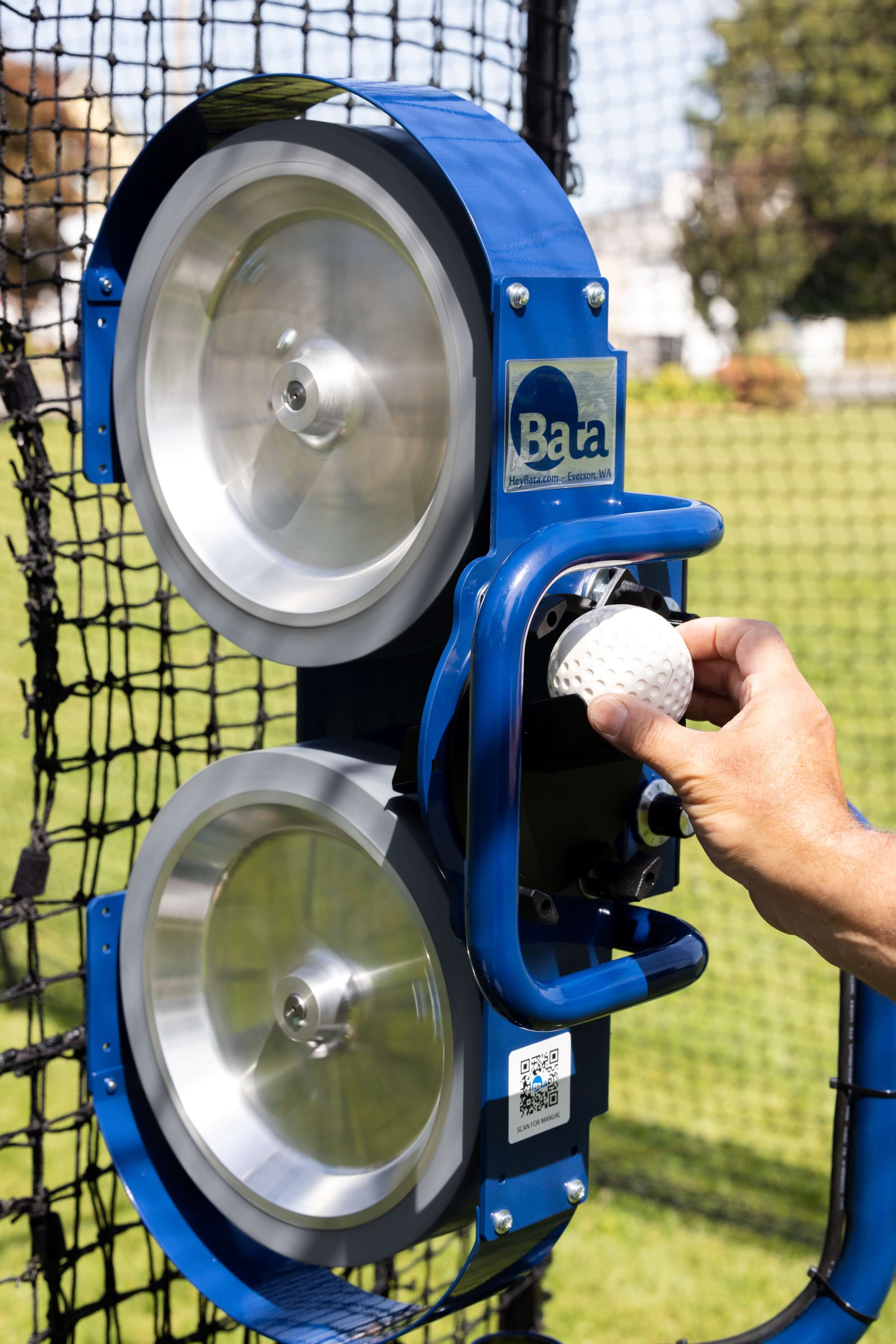 Man feeding baseball into bata 2 pitching machine