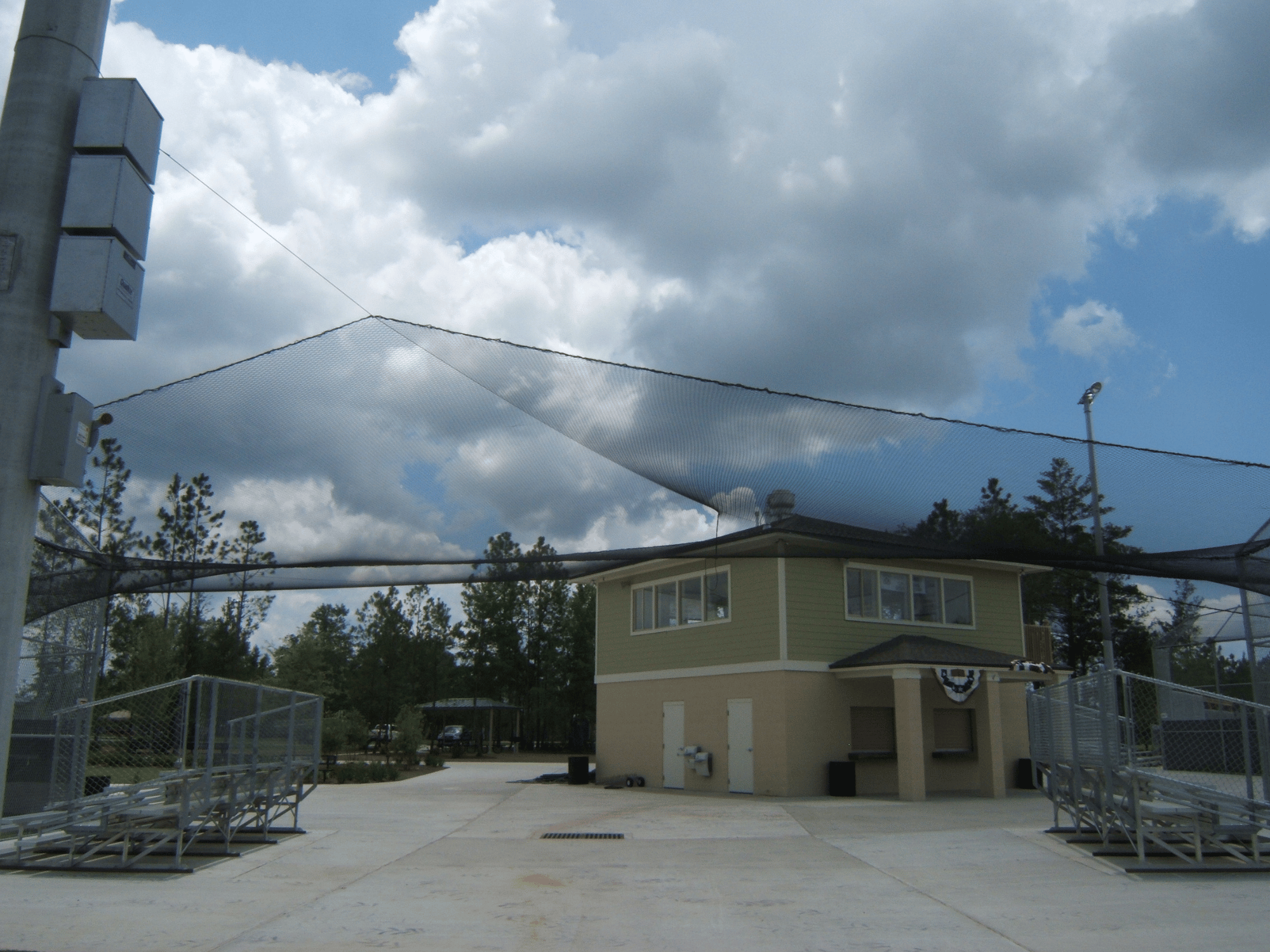 Baseball field foul ball territory netting above bleachers and connected to center building