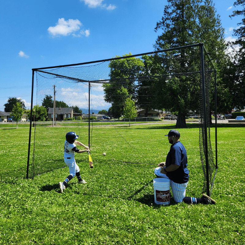 Man soft tossing the baseball to the youth player in our BCI backstop