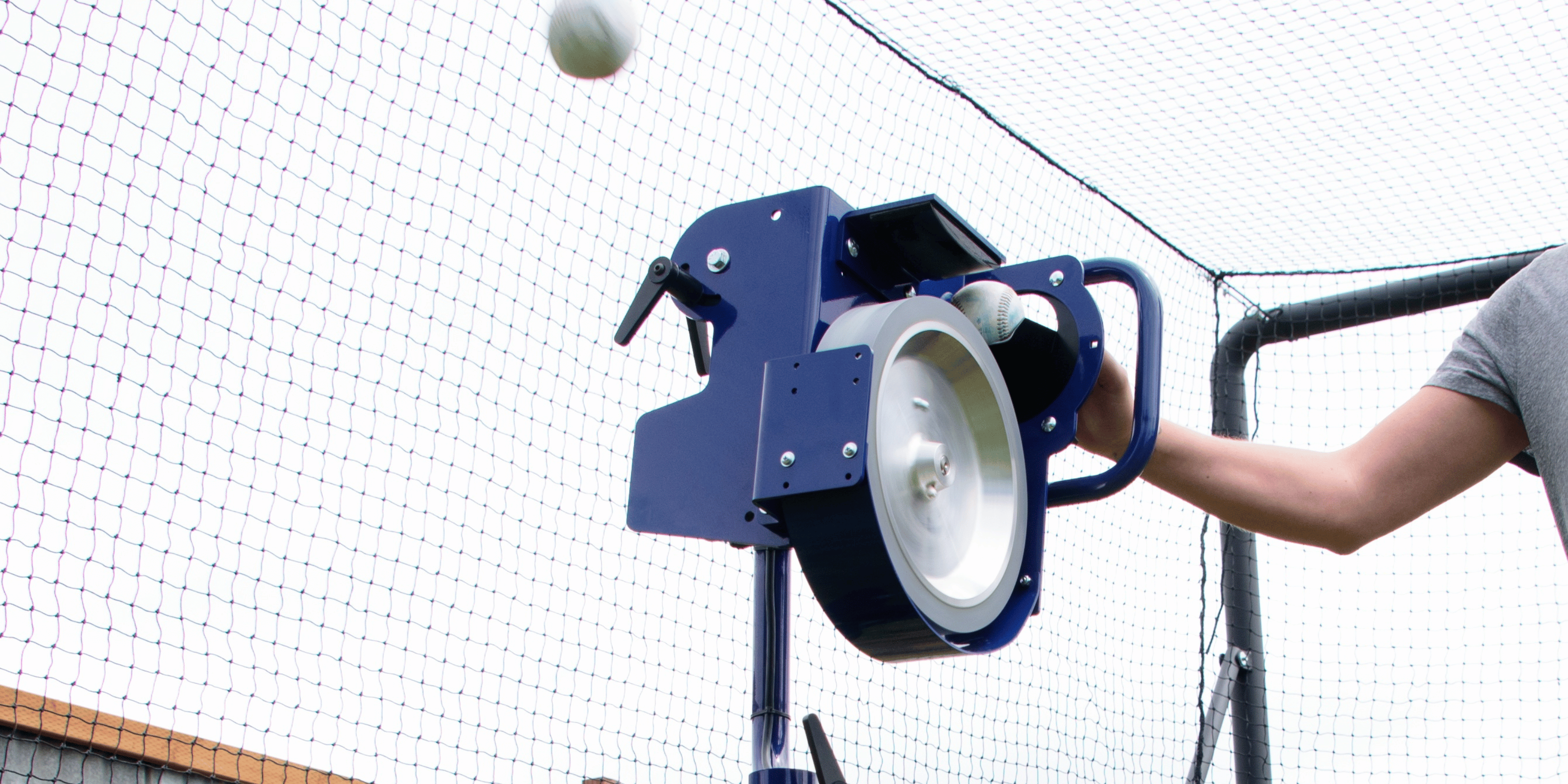 Bata b1 curveball pitching machine being fed by person in batting cage