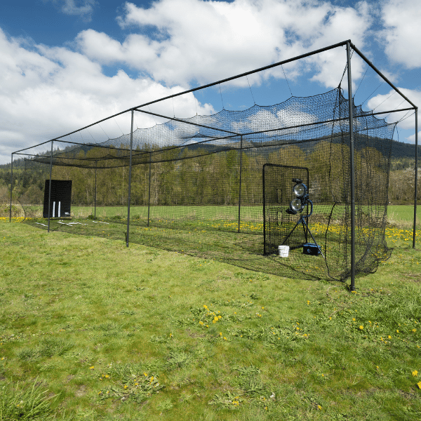 The Thumper Batting Cage in green grassy backyard with blue skies and trees