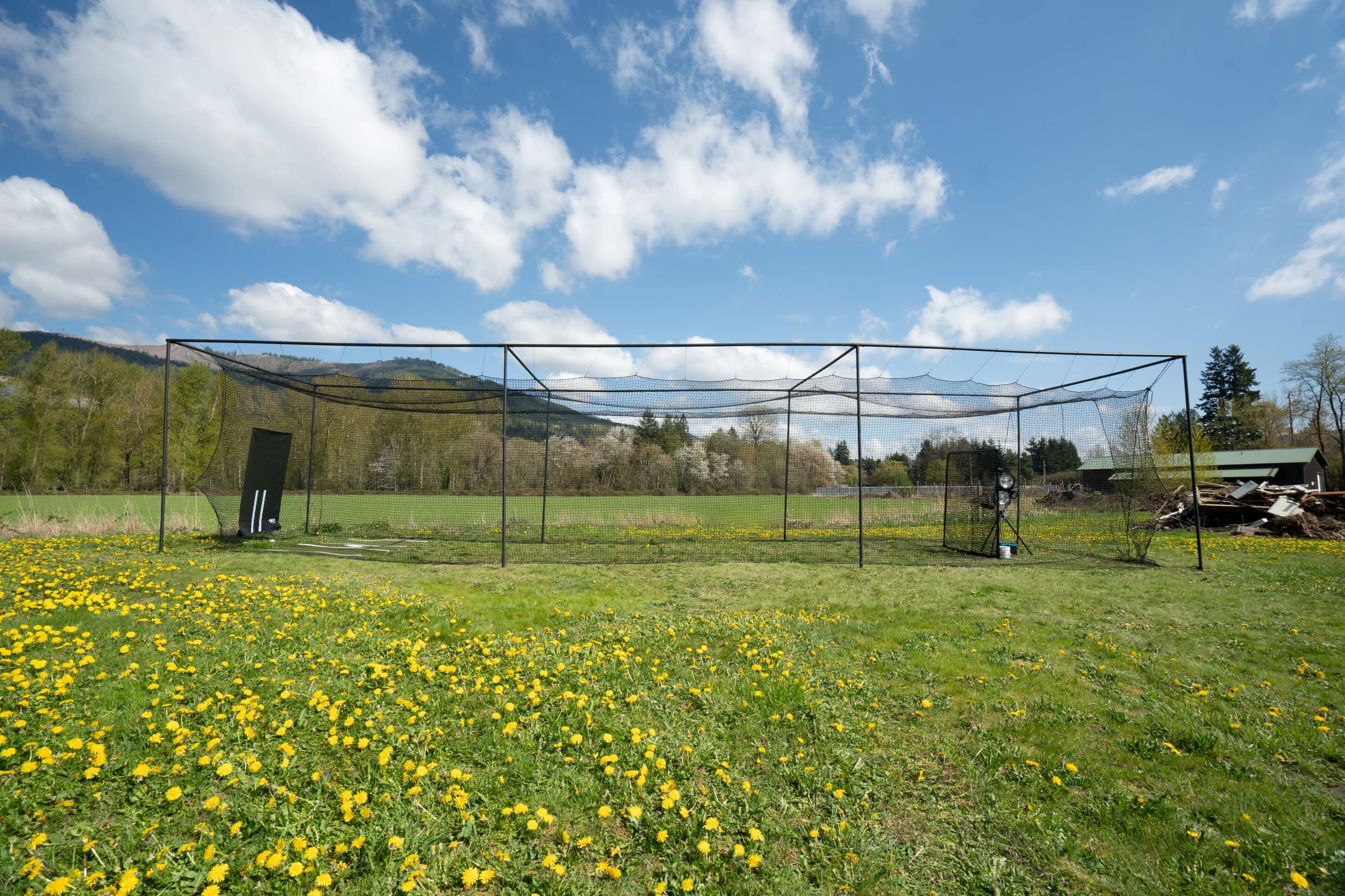 Side of the Thumper batting cage with green grass and blue skies