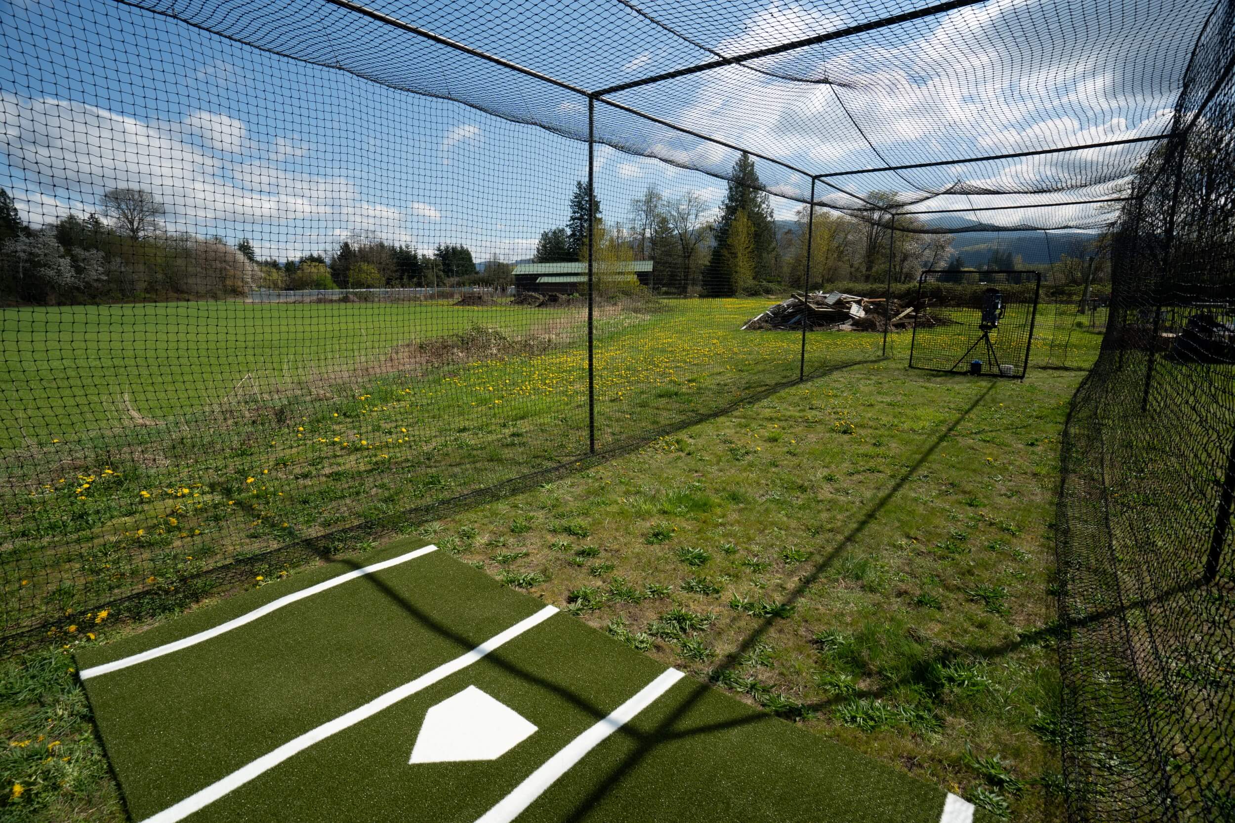 Inside the Thumper batting cage with batters box mat and pitching machine 