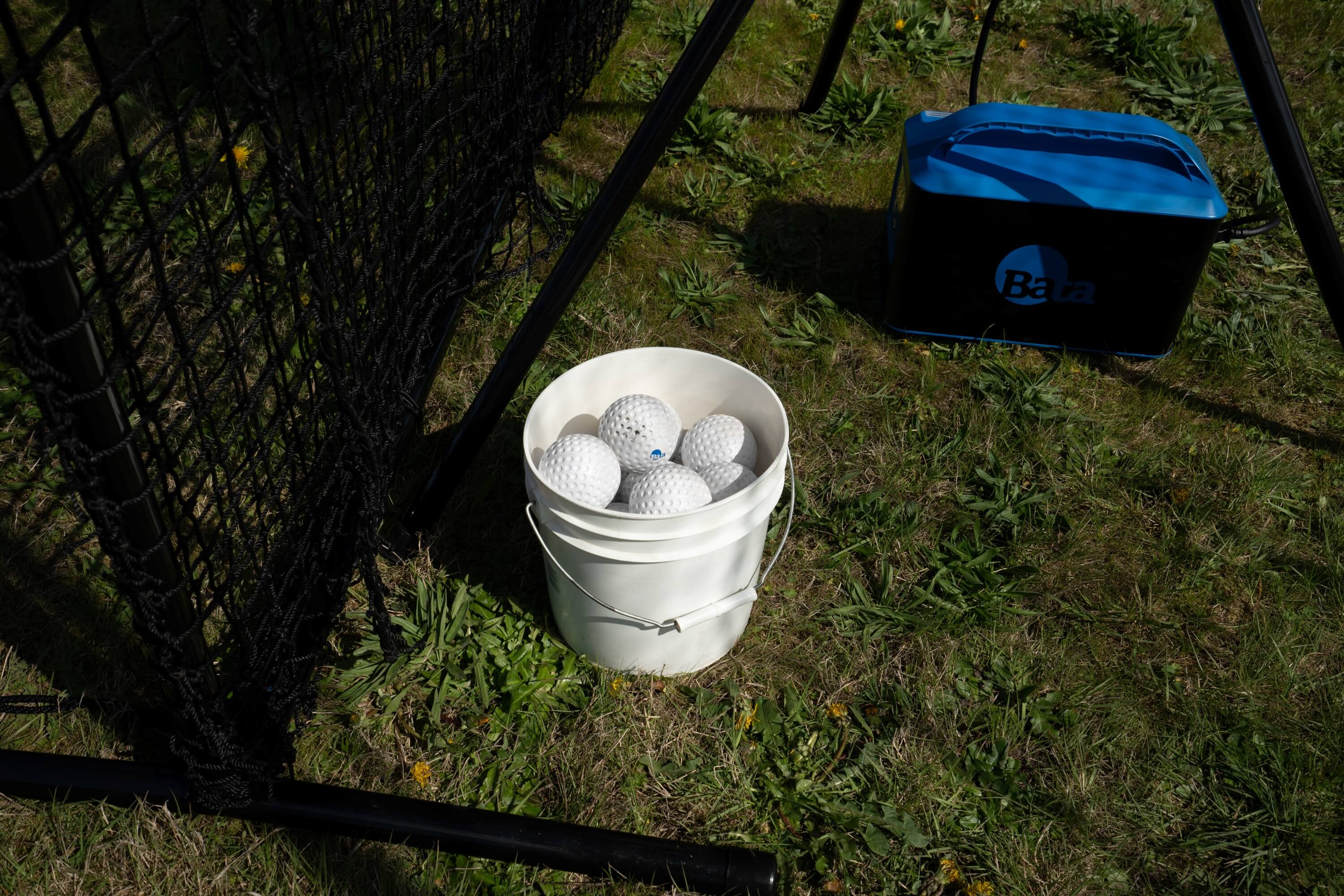 Lightweight bata dimpled baseballs in a bucket with battery and screen