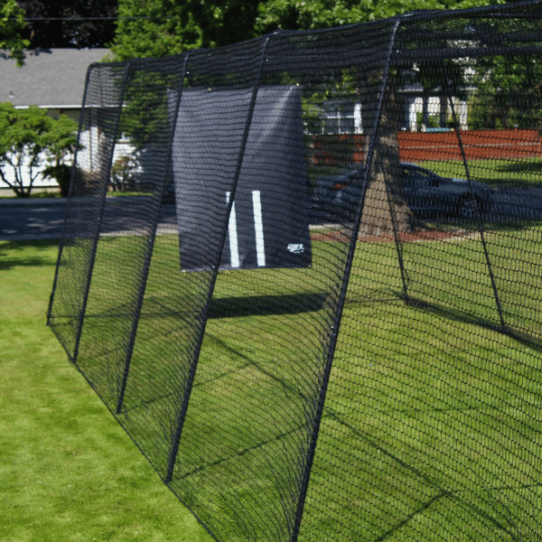 The Trapezoid batting cage on green grass with a vinyl backdrop hung on the end