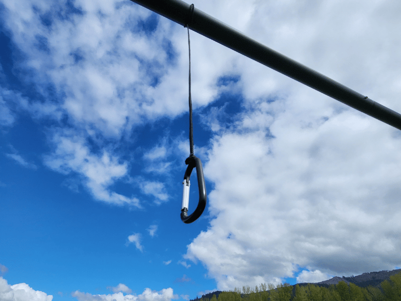 A carabiner hanging from a batting cage pole