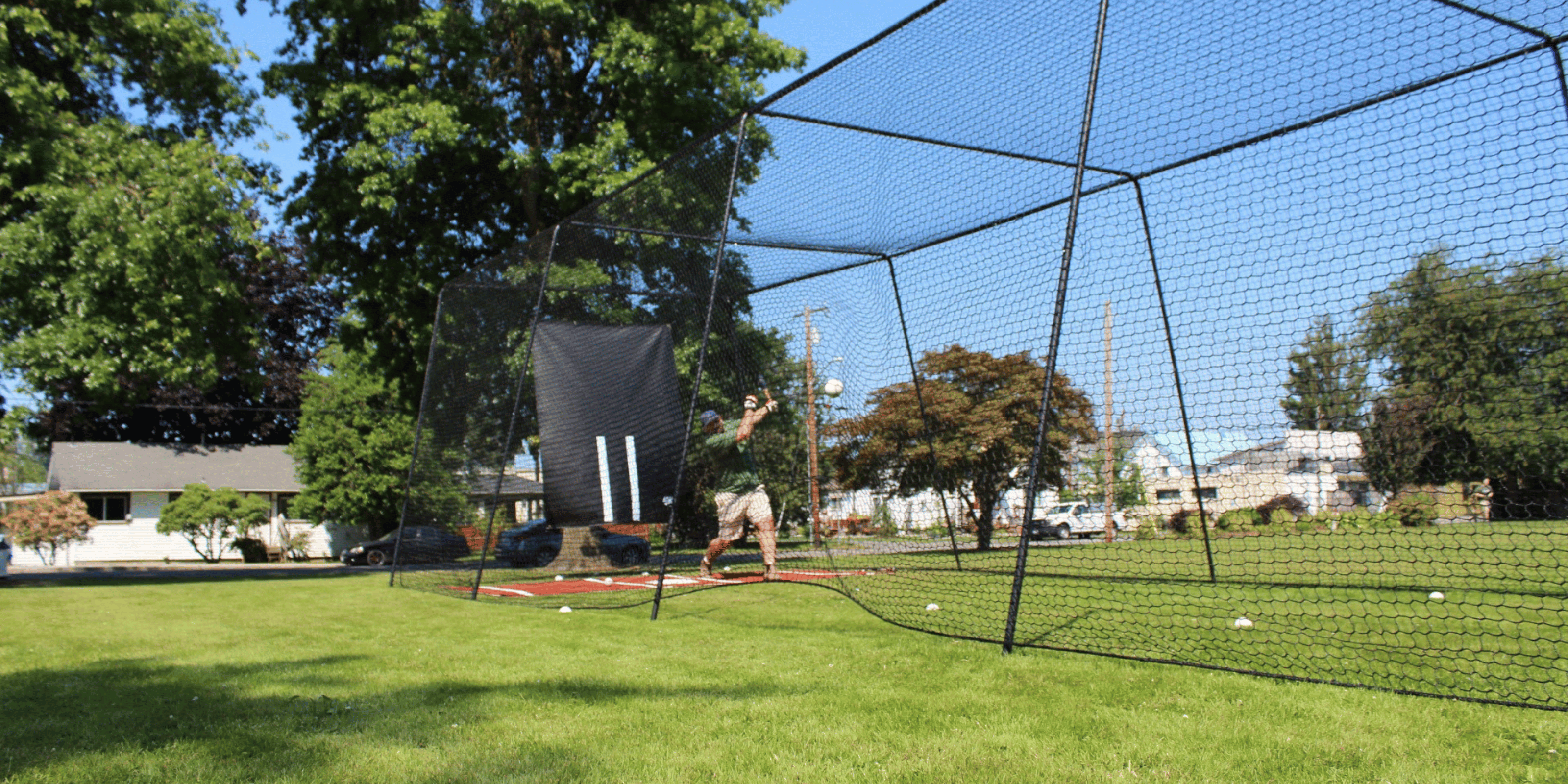 Man batting inside trapezoid batting cage