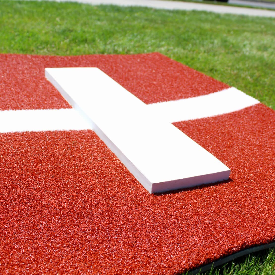 Close up of the pitching rubber on the DuraTurf™ clay Softball Pitcher's Mat on green grass