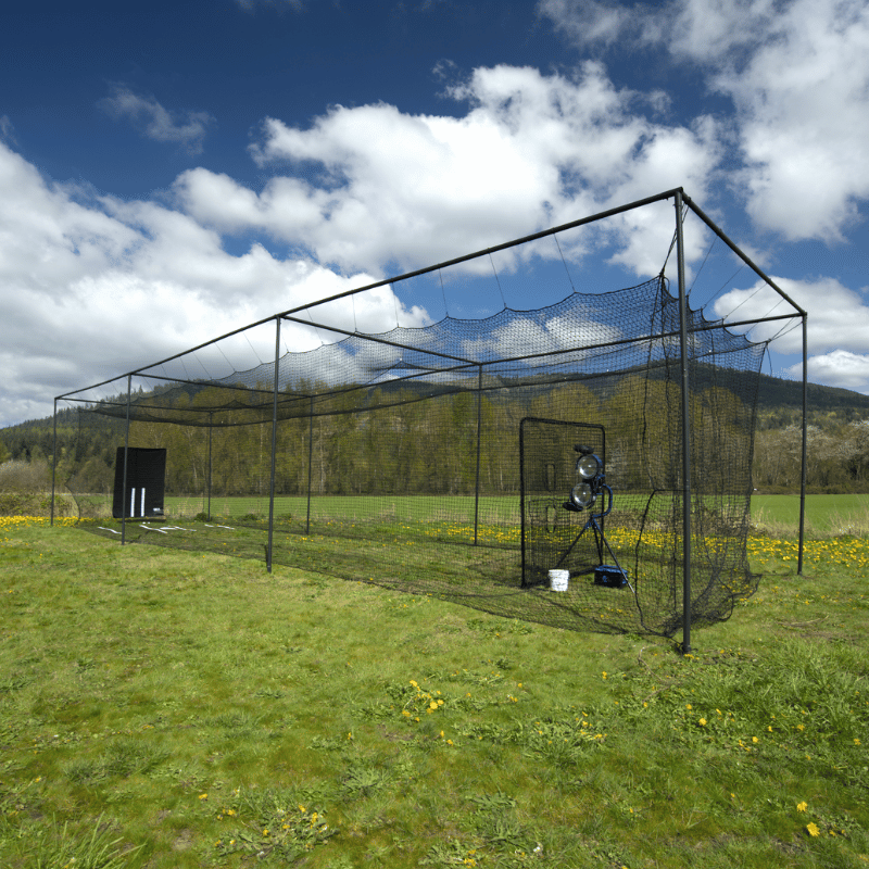 The Thumper Ultra Batting Cage with accessories and with blue cloudy skys above