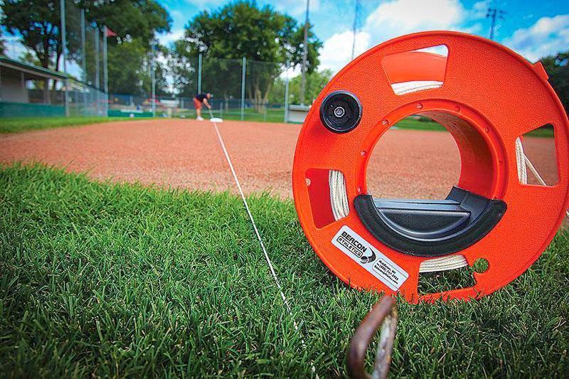 person using the Pro Cord String Winder on the baseball infield