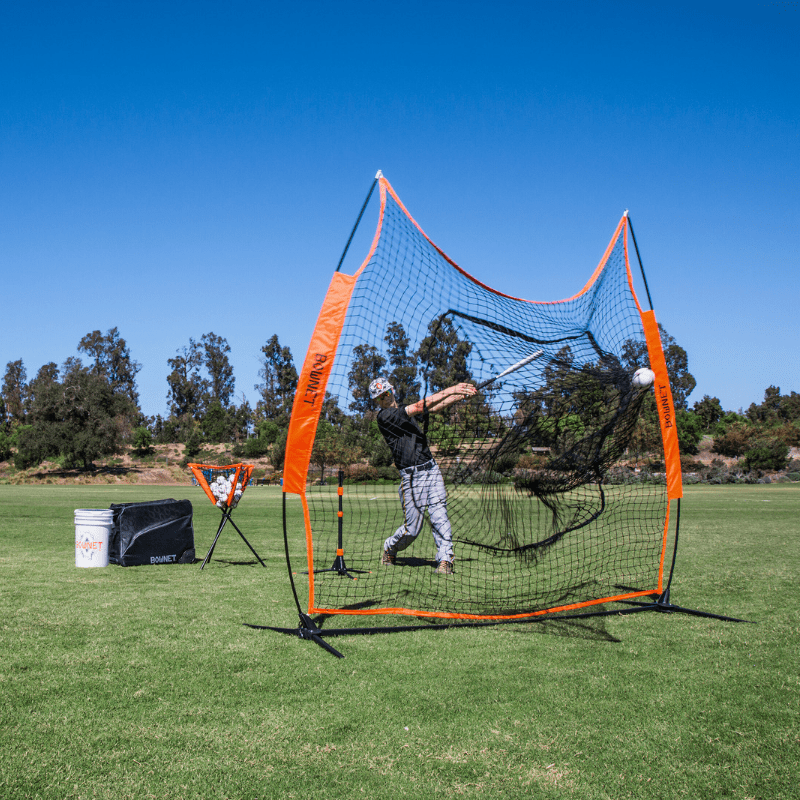 Boy hitting baseballs off a tee into the Big Mouth Portable Sports Net on green grass