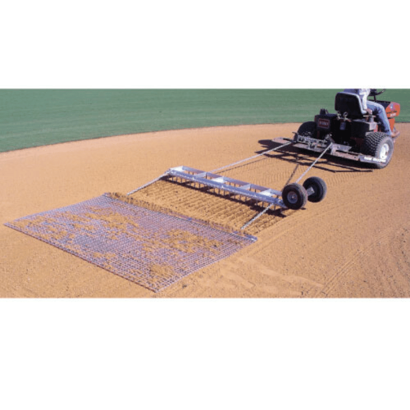 Man using a mower to drag the Diamond Digger Field Groomer drag mat